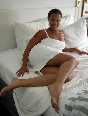 Long legged african slut-wife with a tat posing on the bed.